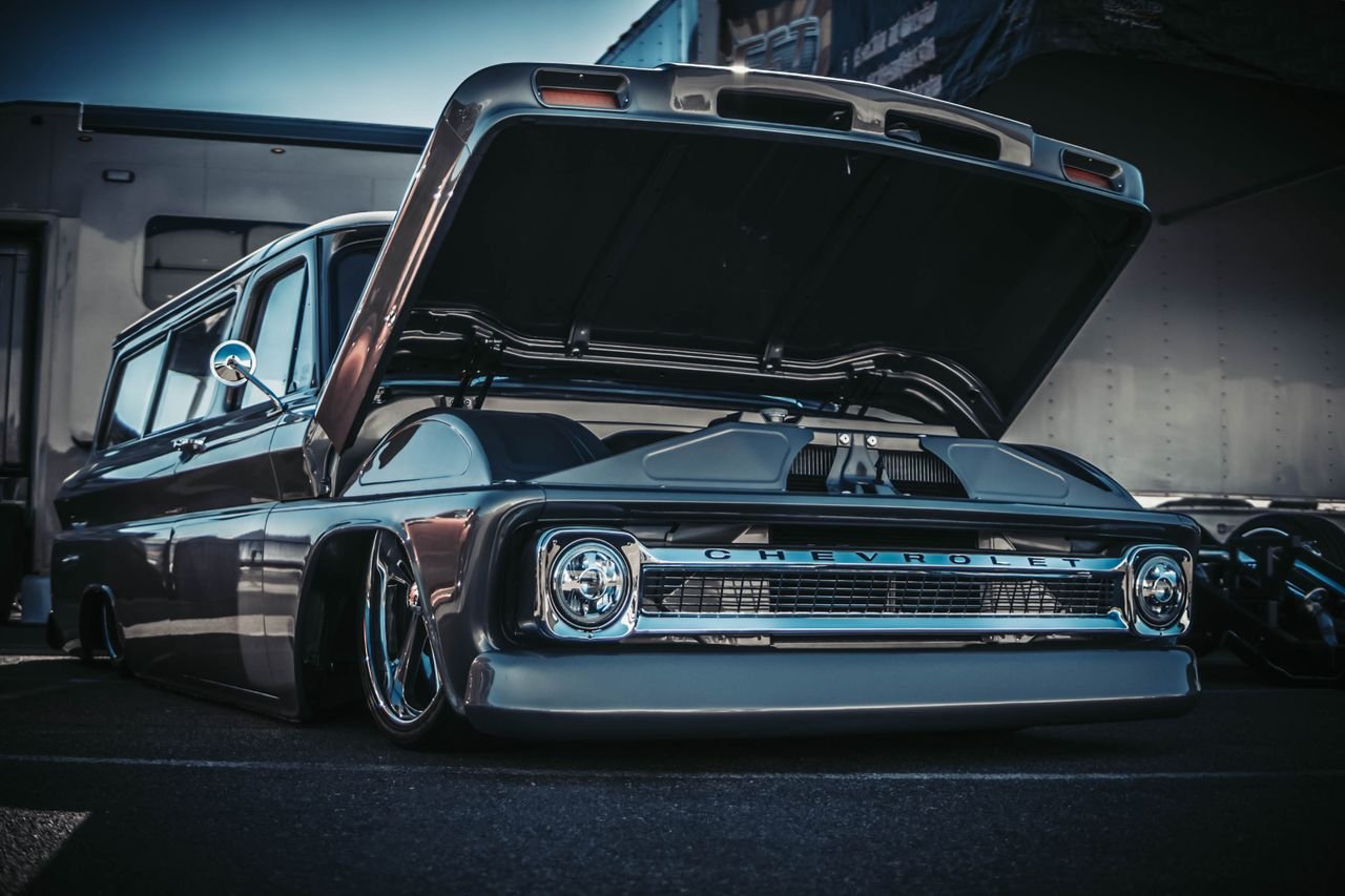 Vintage Chevrolet truck with a low suspension and open hood, showcasing its shiny design.