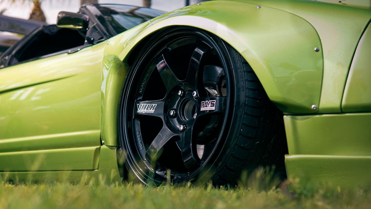Detailed shot of a green sports car featuring sleek, luxury design and race-ready alloy wheels.