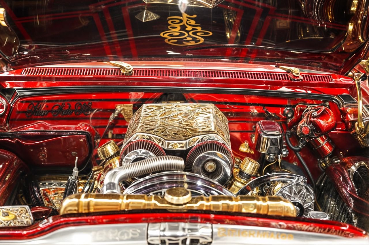 Detailed view of a custom lowrider engine at a New York auto show featuring ornate designs.