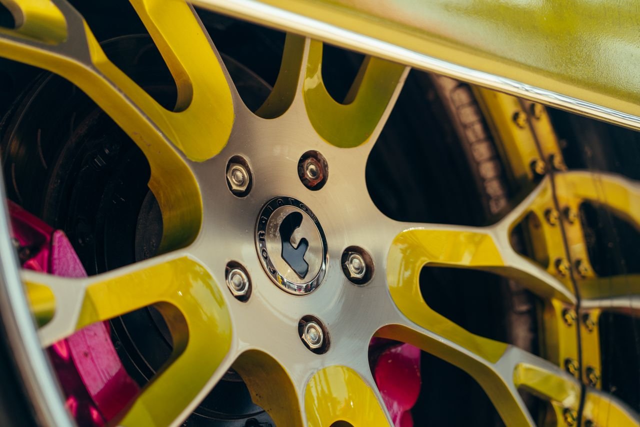 Detailed view of a colorful custom car wheel with yellow spokes and a unique design.
