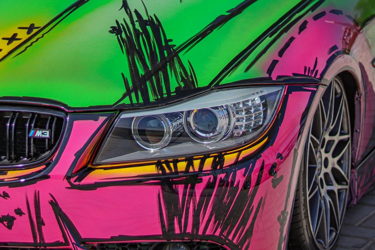 Close-up of a custom-painted car with a vibrant graffiti design in daylight.